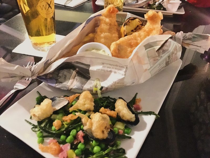Battered plaice and chips in boat-shaped newspaper wrapping, served with Peas de Gallos