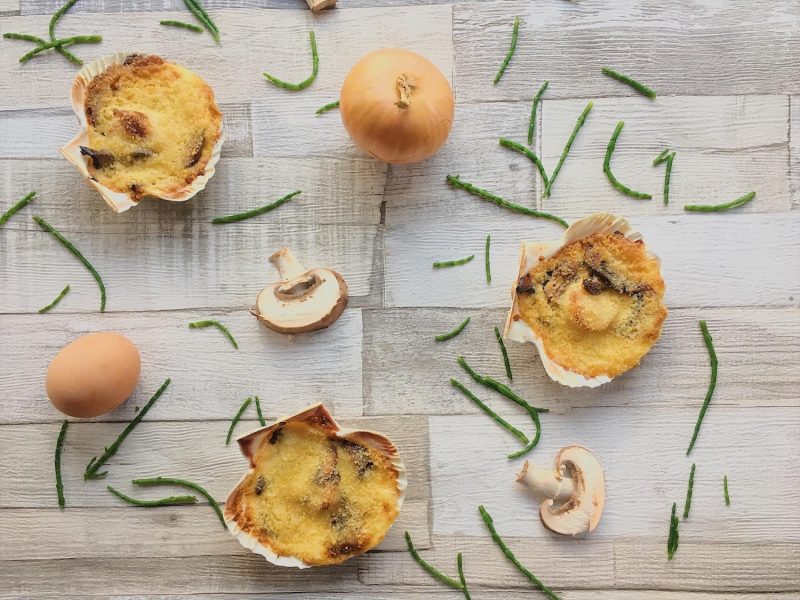 Coquilles St Jacques arranged alongside sliced mushrooms, whole onions and samphire
