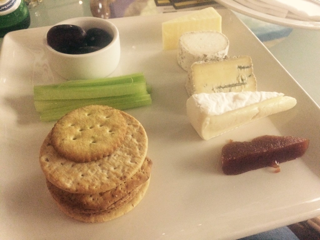 A selection of cheeses, crackers, grapes, quince jelly and celery on a plate