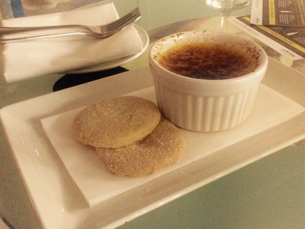 Creme brulee in a ramekin served alongside two shortbread biscuits
