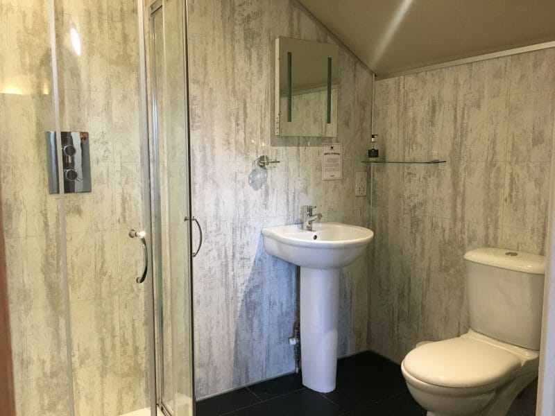 The upstairs bathroom in a Tenby lodge at Bluestone Wales, with a shower cubicle, sink and toilet