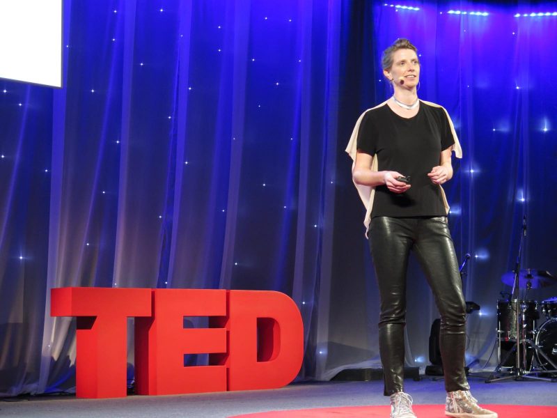 Julie Freeman on stage at a TED talk - a potential way to stay entertained on a long-haul flight