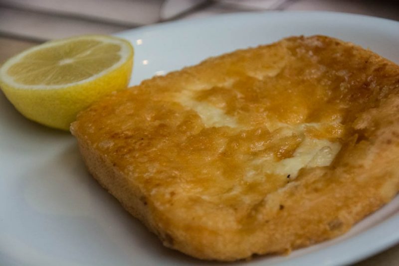 Saganaki, a traditional Greek food of sheep or goat's millk cheese served heated, with a wedge of lemon.