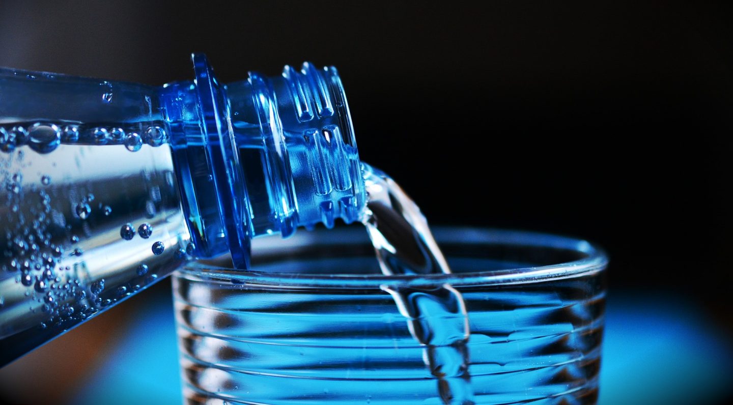 Bottled water being poured into a glass. Drinking bottled water is a good idea if you want to avoid holiday sickness when travelling to certain developing countries.