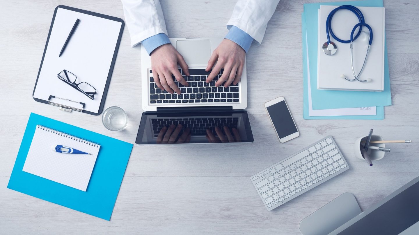 A flatlay of a doctor's desk, complete with a stethoscope.