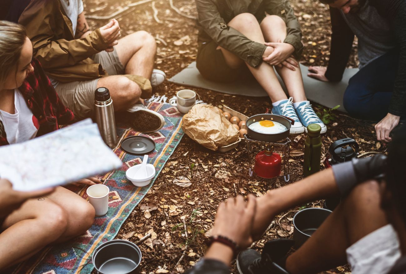 Group getaway: friends sat around a camping stove
