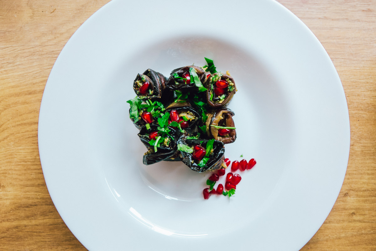 Georgian eggplant recipe consisting of aubergine strips spread with walnut paste, rolled up and garnished with pomegranate seeds.