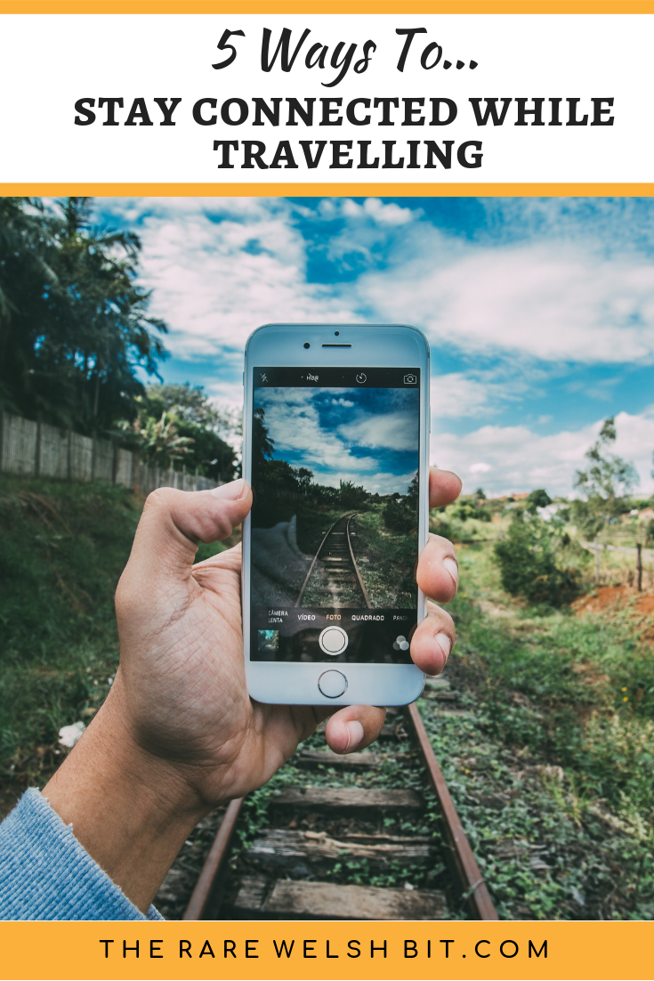 A hand holding an iPhone, taking a photo of a railway track