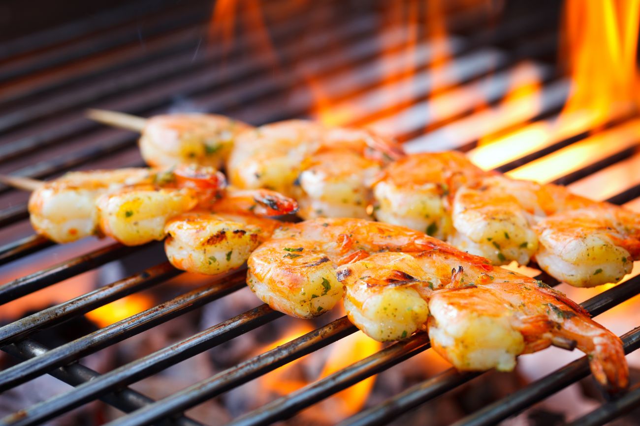 Prawns on a skewer cooking on a barbecue