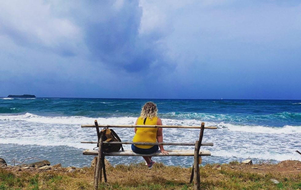 Girl sitting on bench looking out to the sea