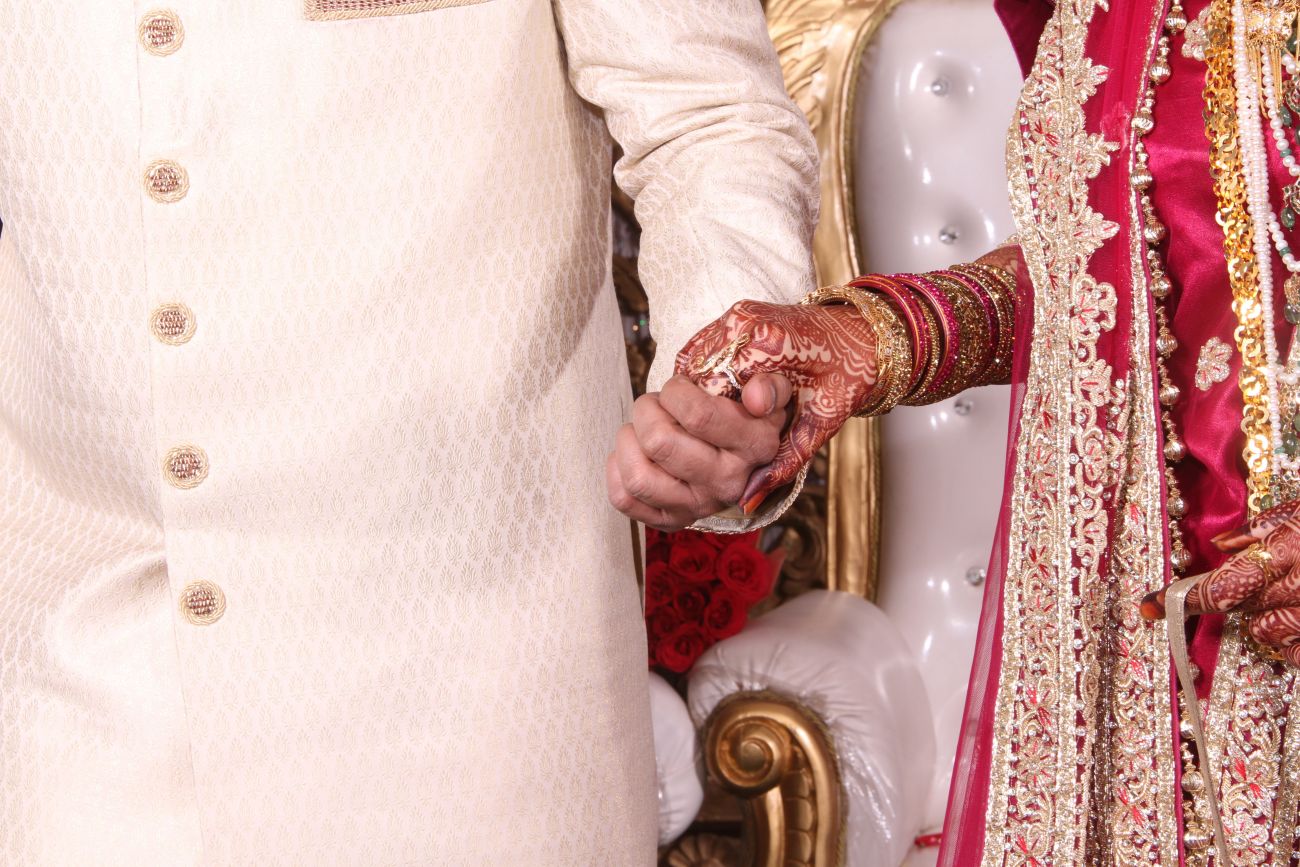 Indian groom takes his bride's hand in a close-up shot.