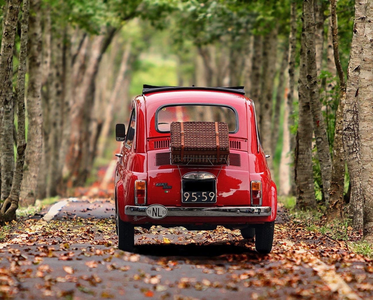 A foreign car with a wicker basket tied to the back.