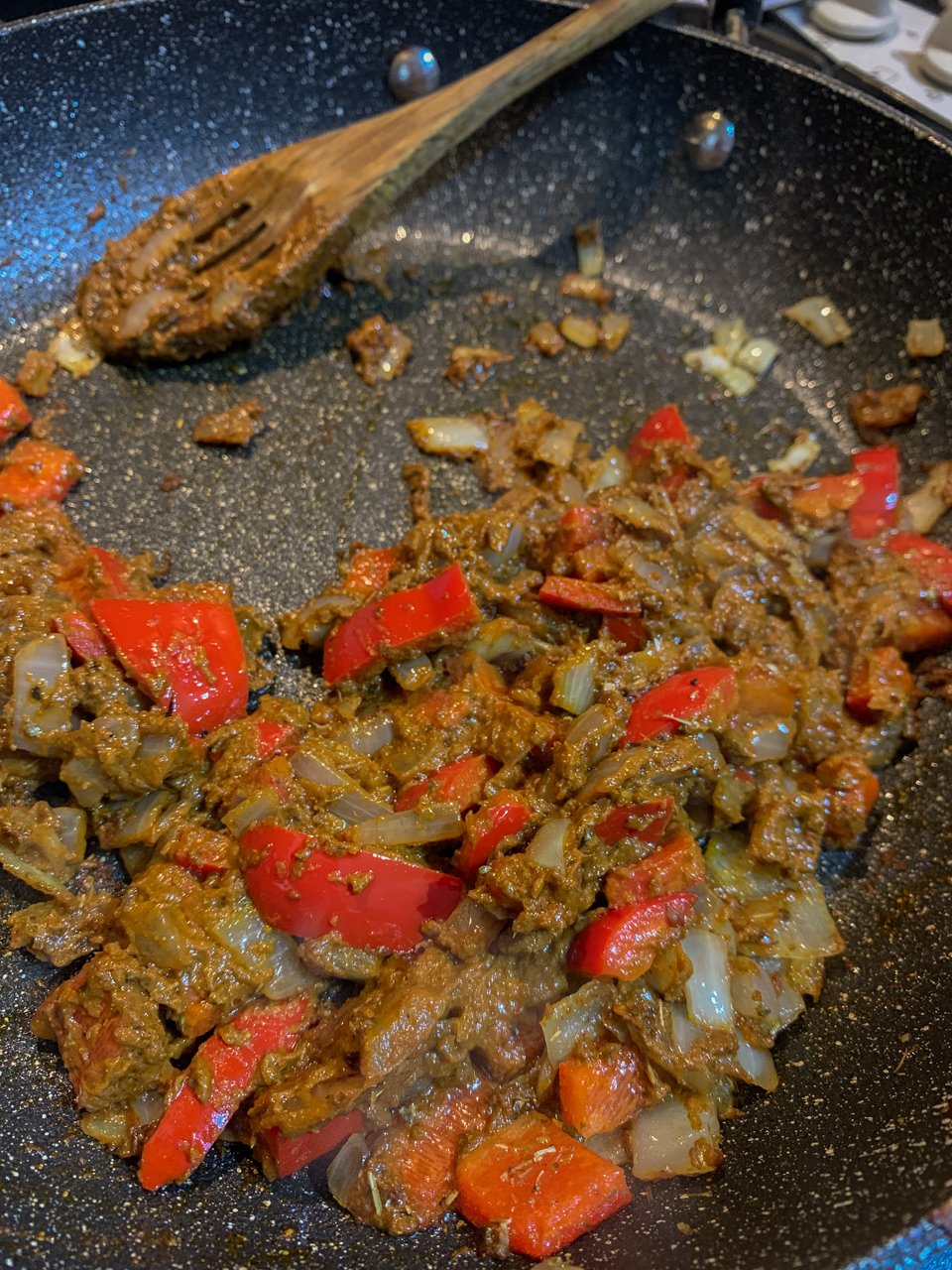 Cooking ancho chilli paste with red bell peppers, onions and garlic