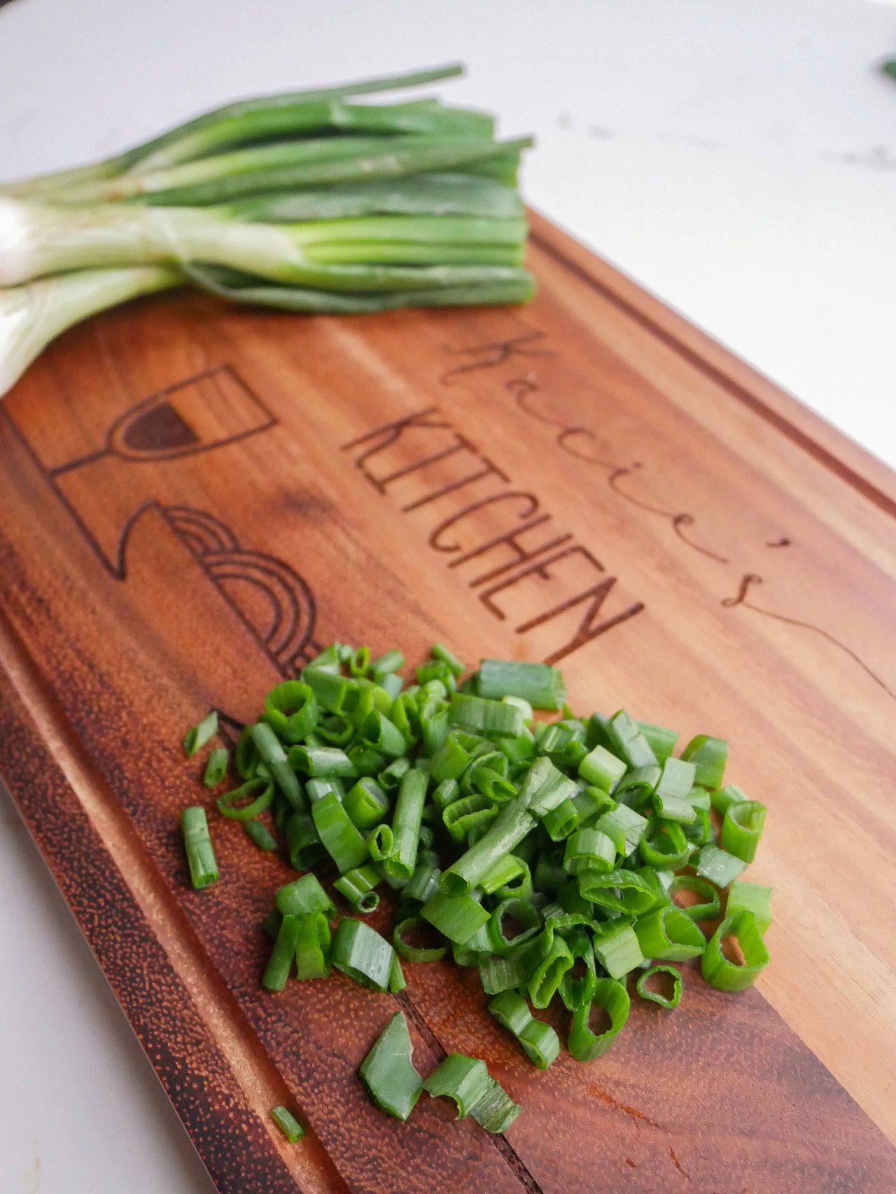 Spring onion sitting on a personalised chopping board, sliced and unsliced