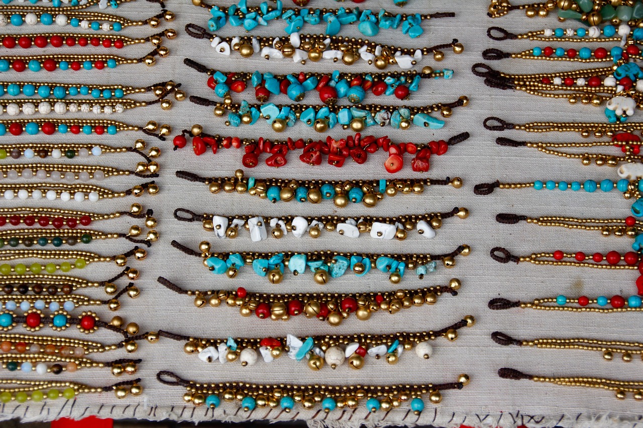 Colourful beaded jewellery laid out on display on a white cloth