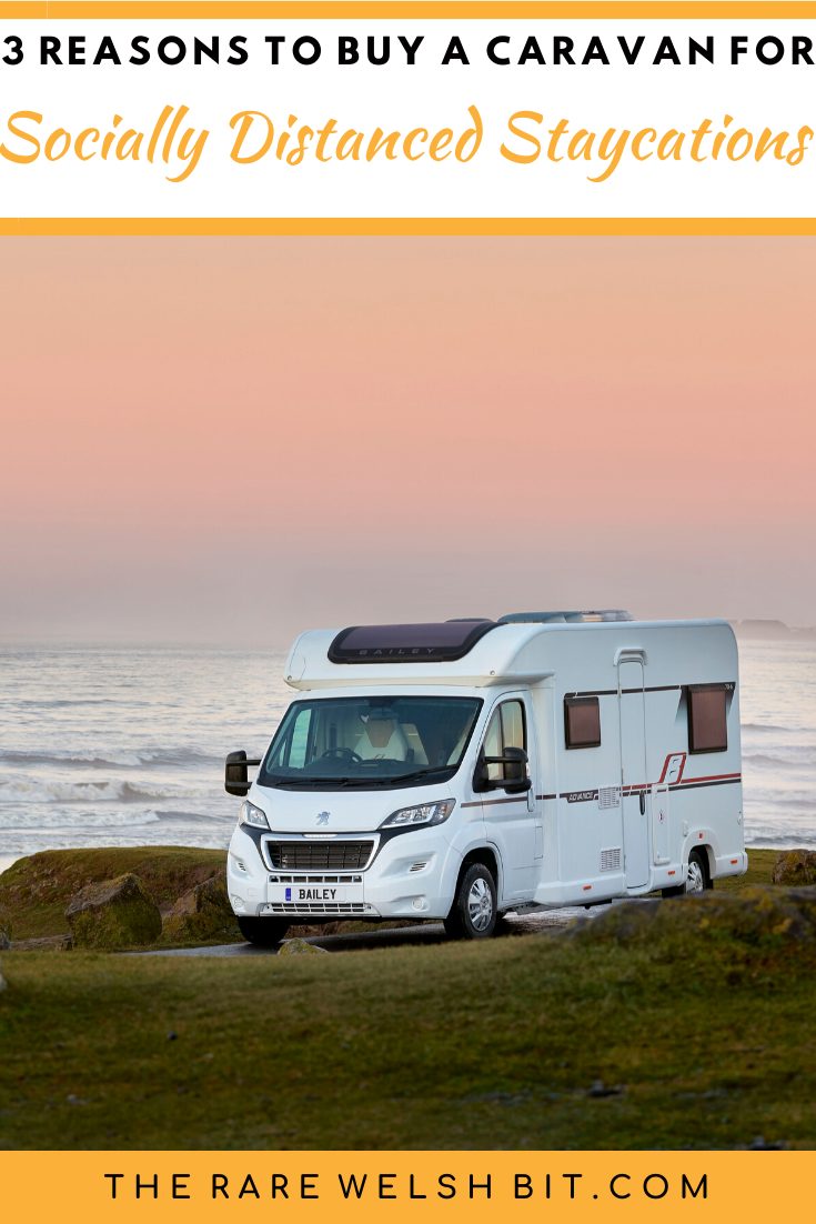 A caravan/motorhome parked up on a grassy bank somewhere on the coast.