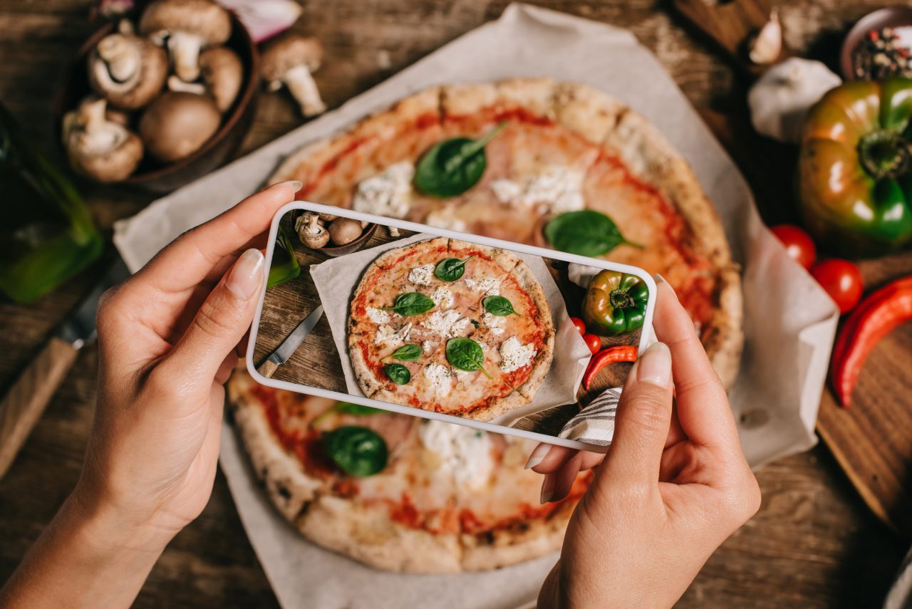 Someone taking a photo of a pizza on their phone from above