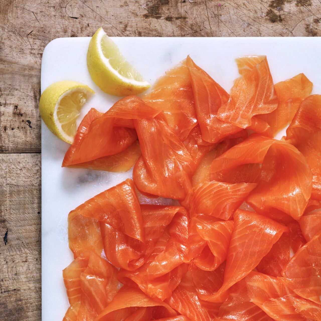 Fresh salmon (smoked) on a chopping board with lemon wedges