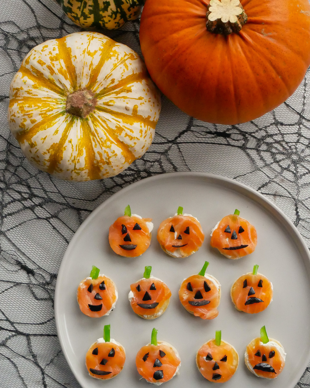 Smoked salmon canapes on a plate next to a pumpkin and squash