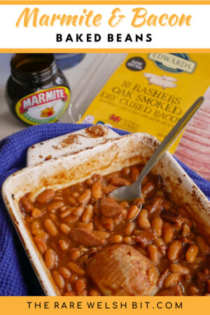 Baked beans in an oven dish with Marmite and bacon in the background
