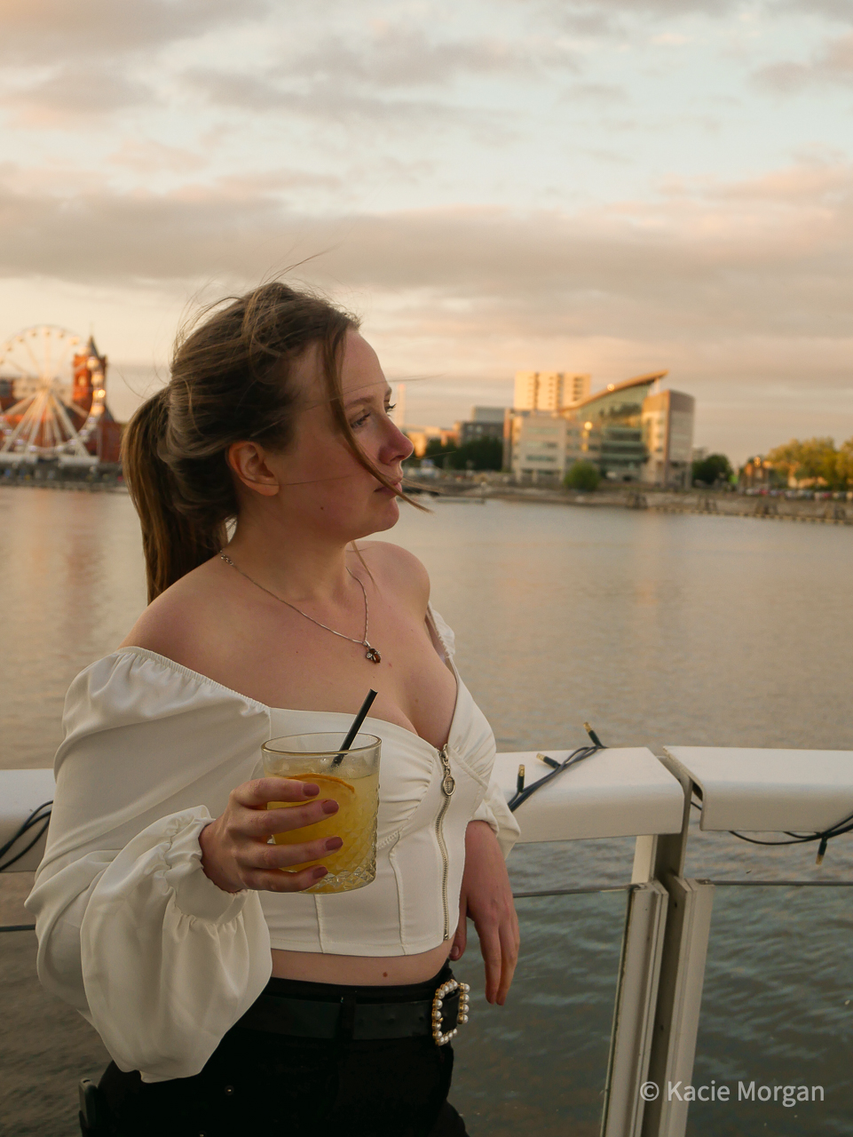 A girl wearing a milkmaid top while holding a cocktail