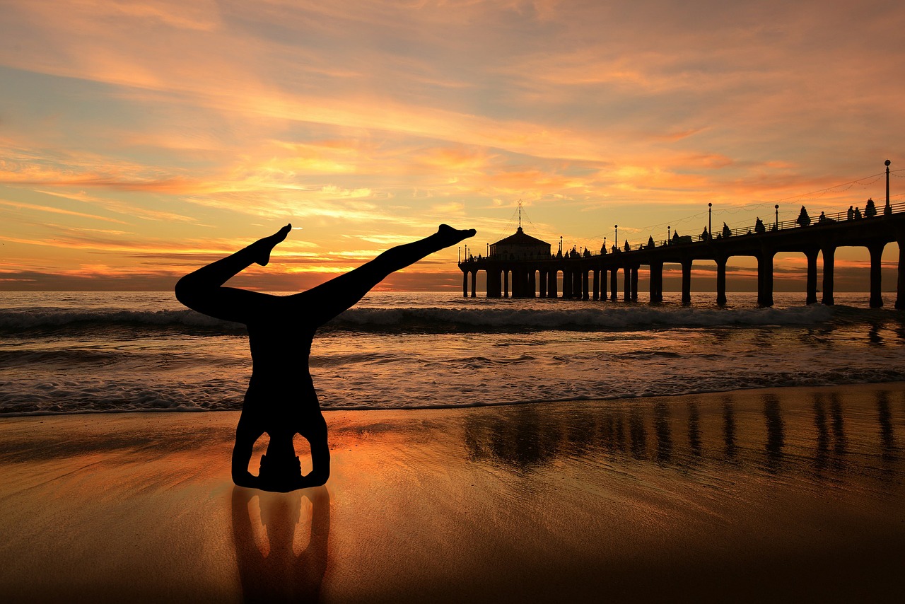 A man doing a yoga headstand on the beach