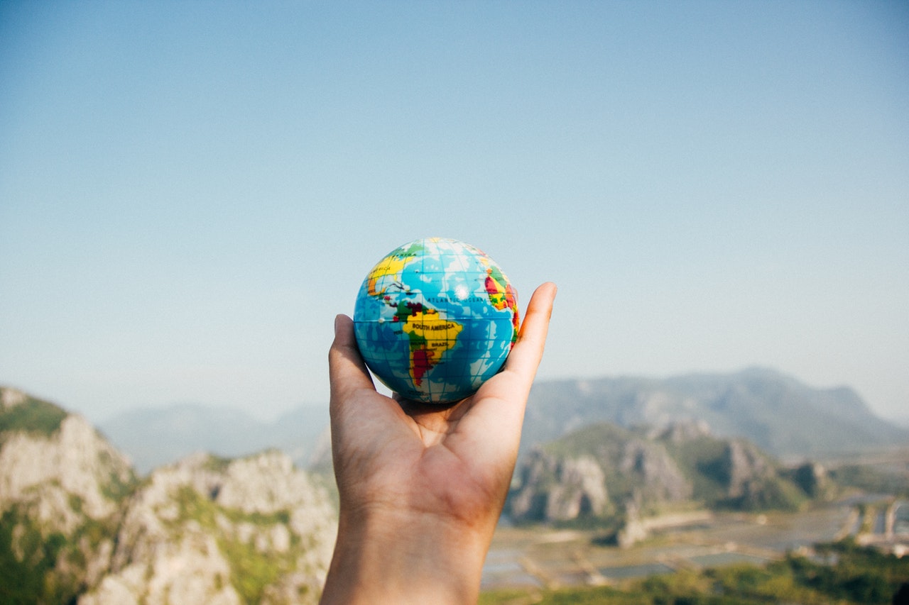 A hand holding a small plastic globe
