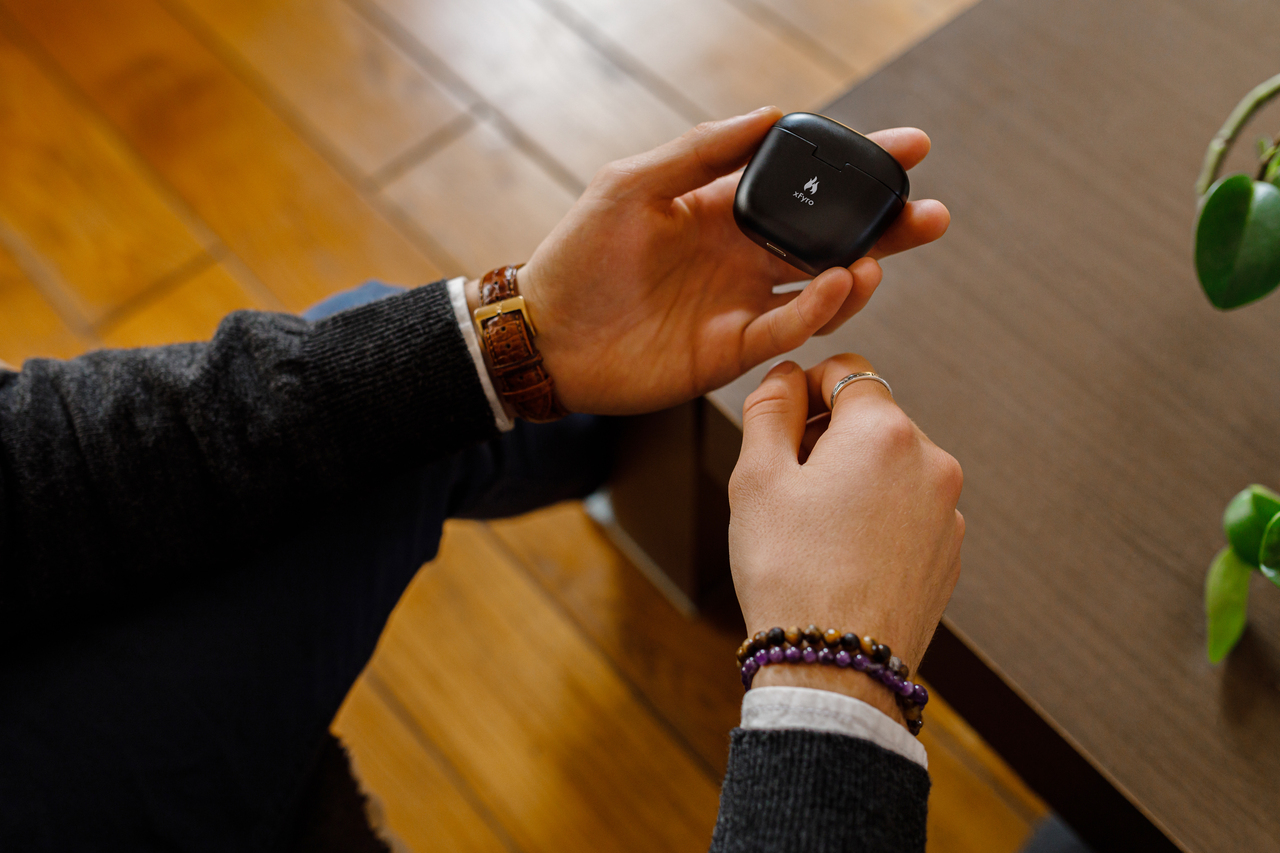 A man holding a pair of xFyro ANC Ear Buds in their case.