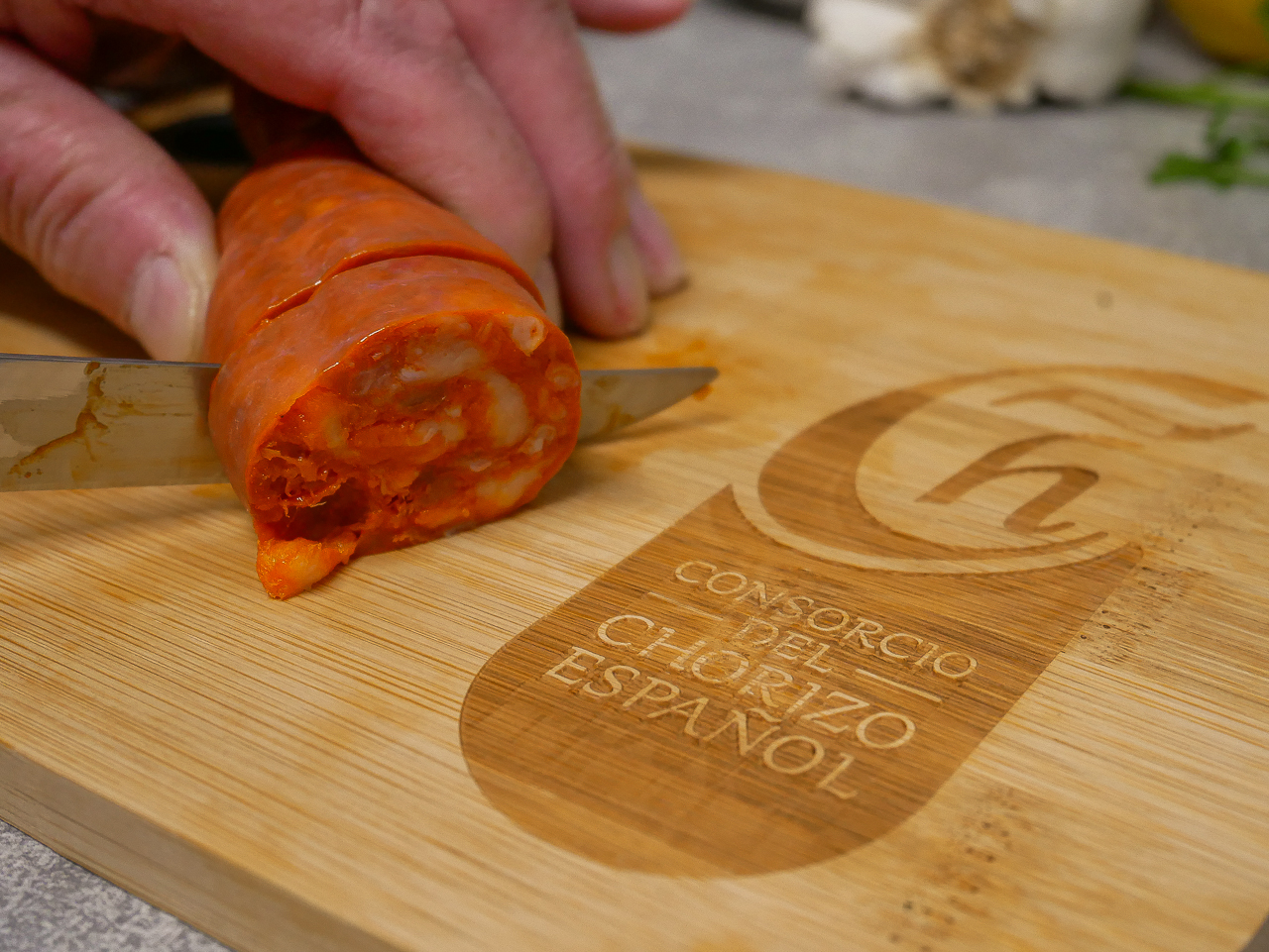 Slicing Spanish chorizo on a chopping board.