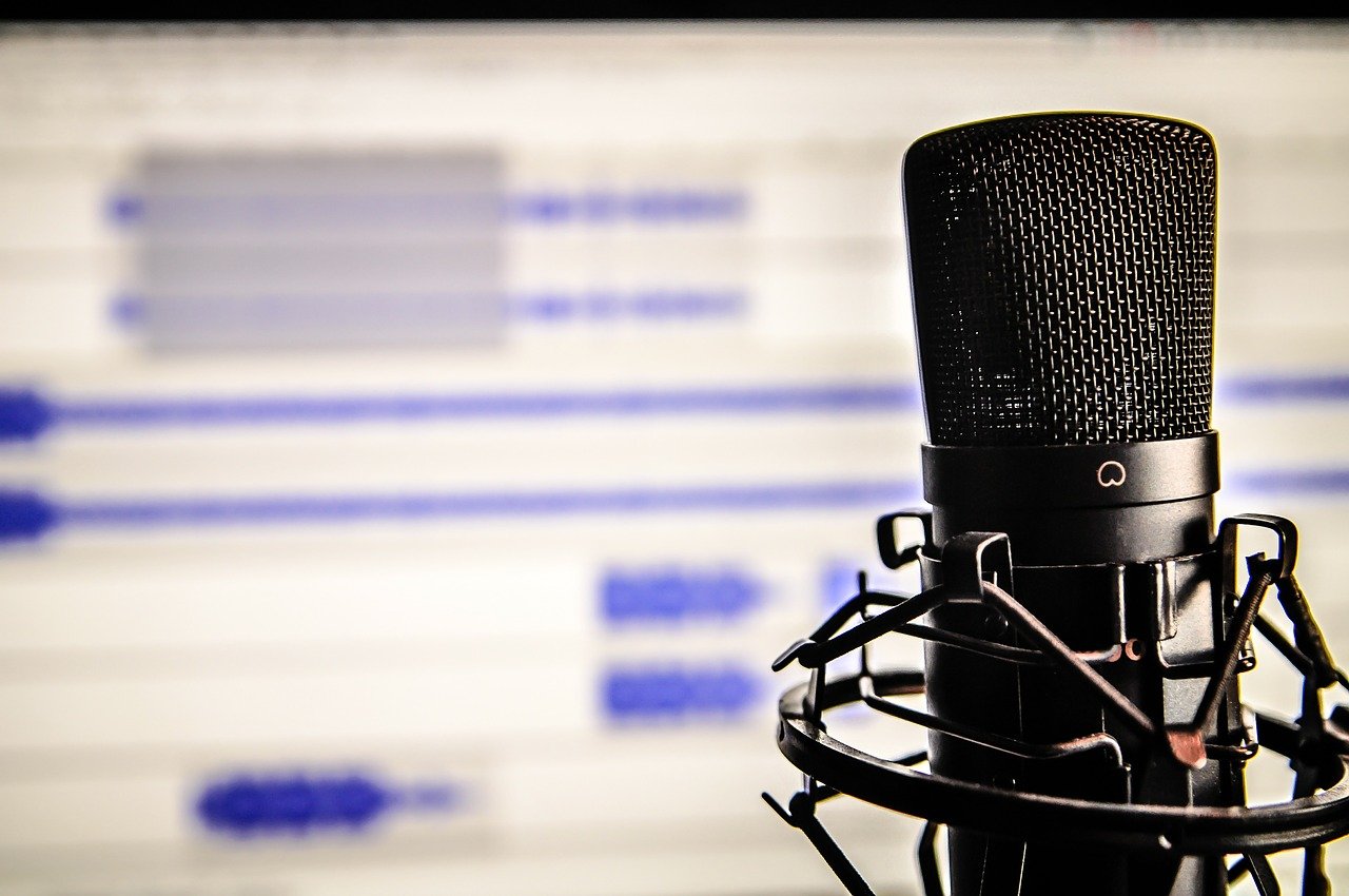 A microphone close-up with audio recording screen in the background