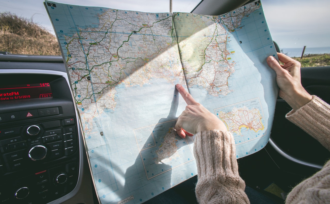 A female reading an map/atlas while in the car.
