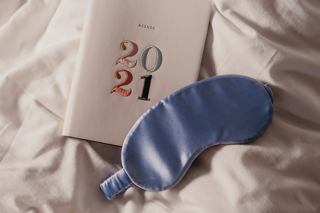 2021 diary and lilac satin eye mask on a bed