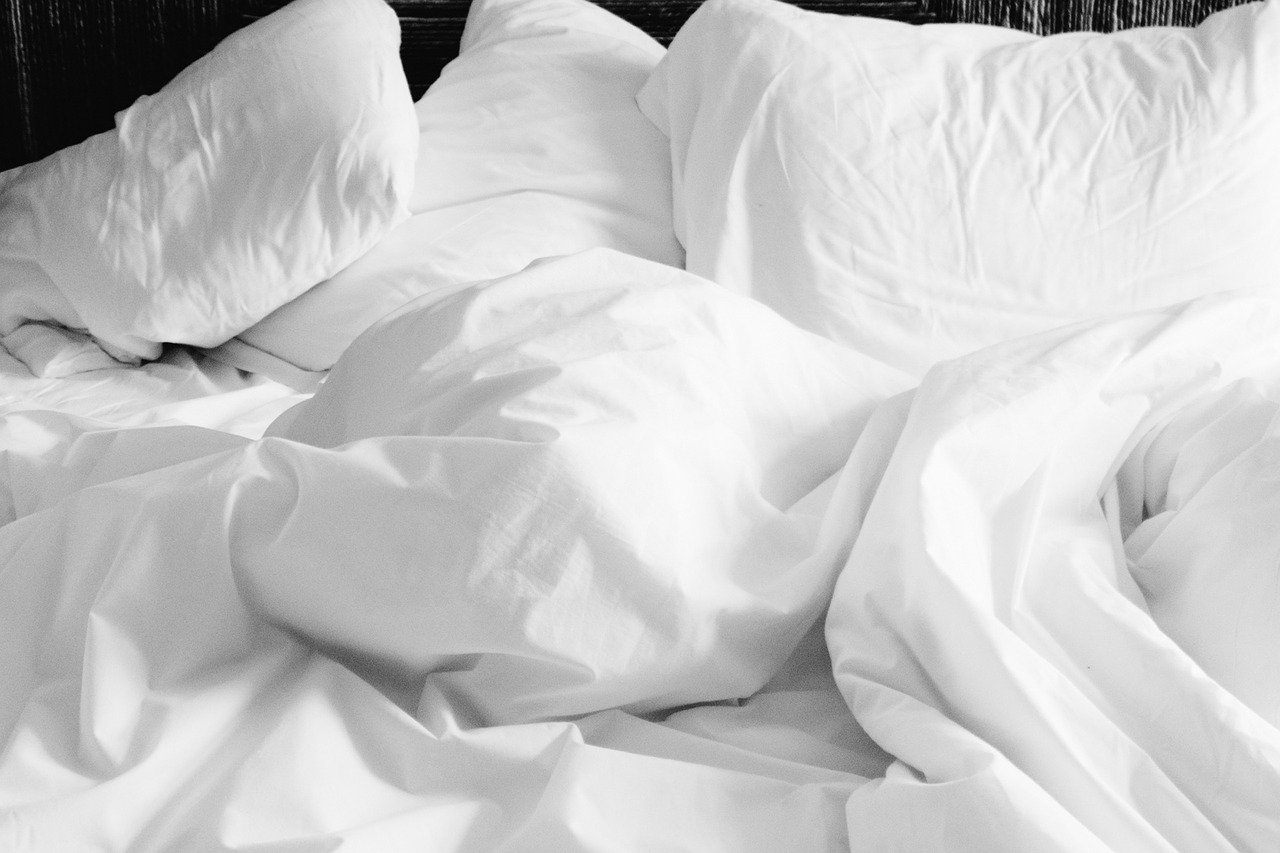 White pillows and bed linen, scrumpled up on a bed
