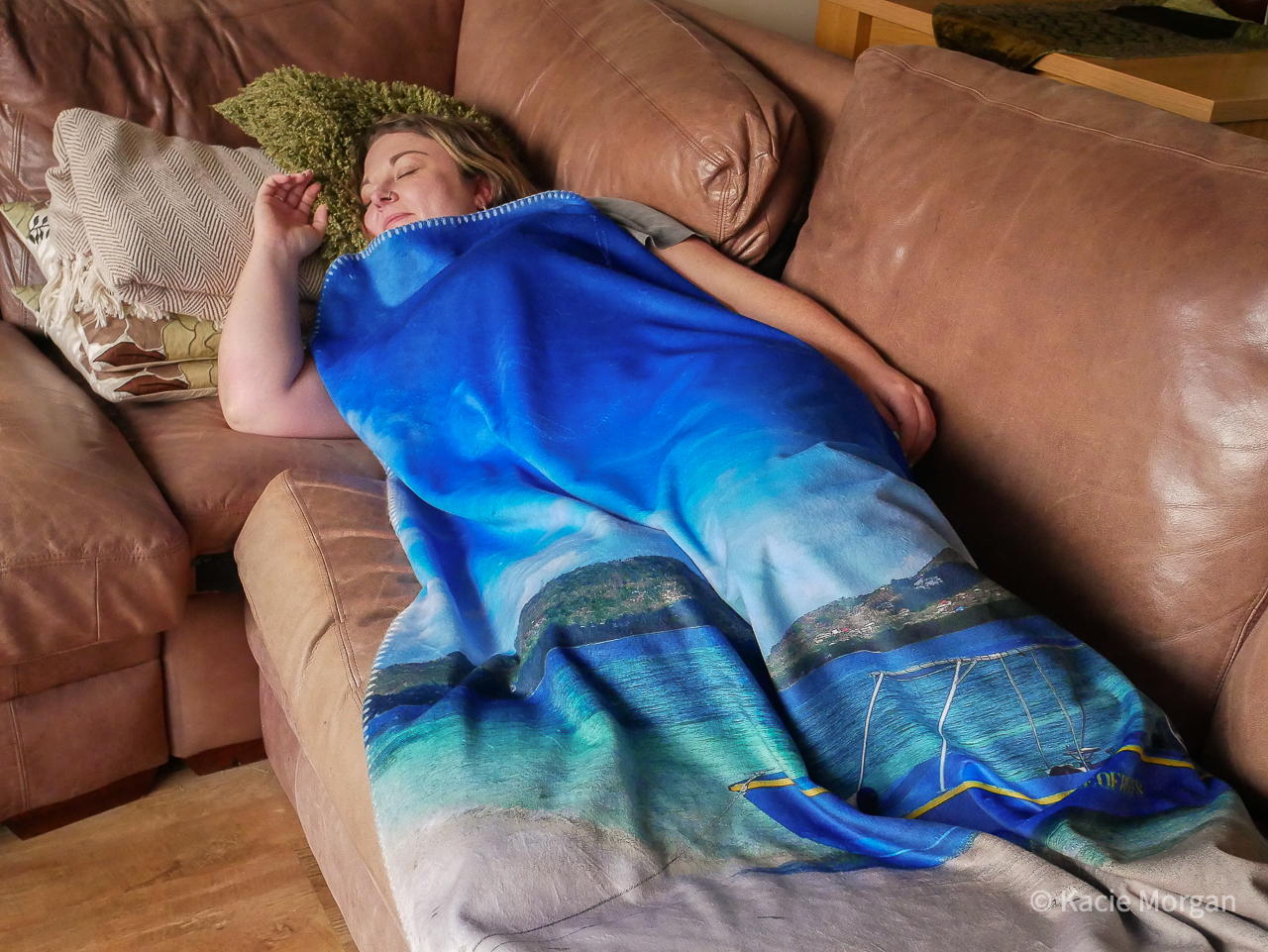 A girl laying on a sofa, covered by a personalised blanket featuring a beach scene.