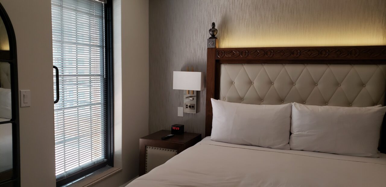 A bed in a hotel room next to a window with blinds down