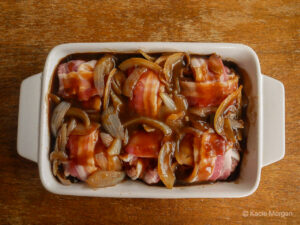 Faggots covered in gravy in a dish, ready to go into the oven