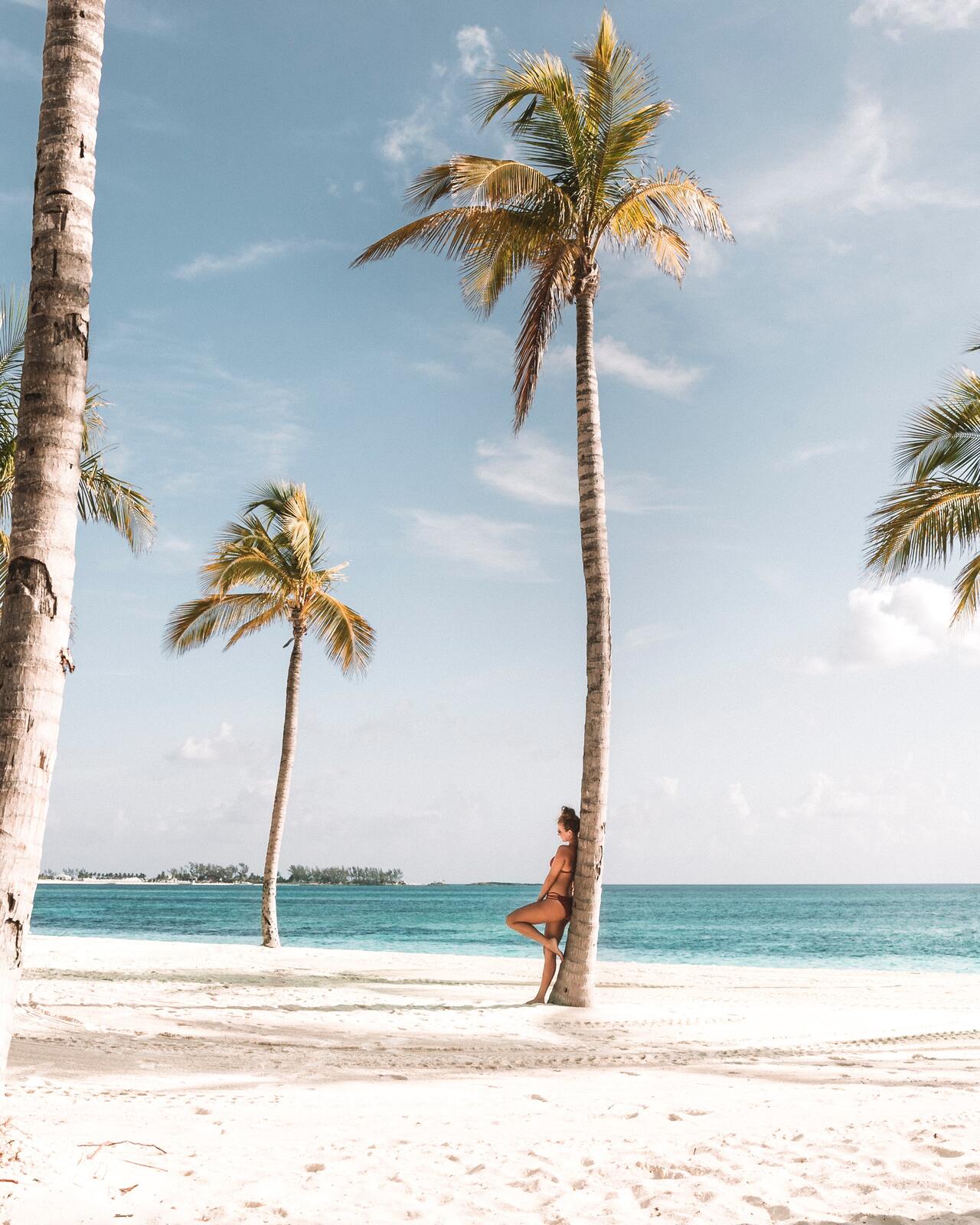 Woman leaning against palm tree at Oberoi Beach Resort