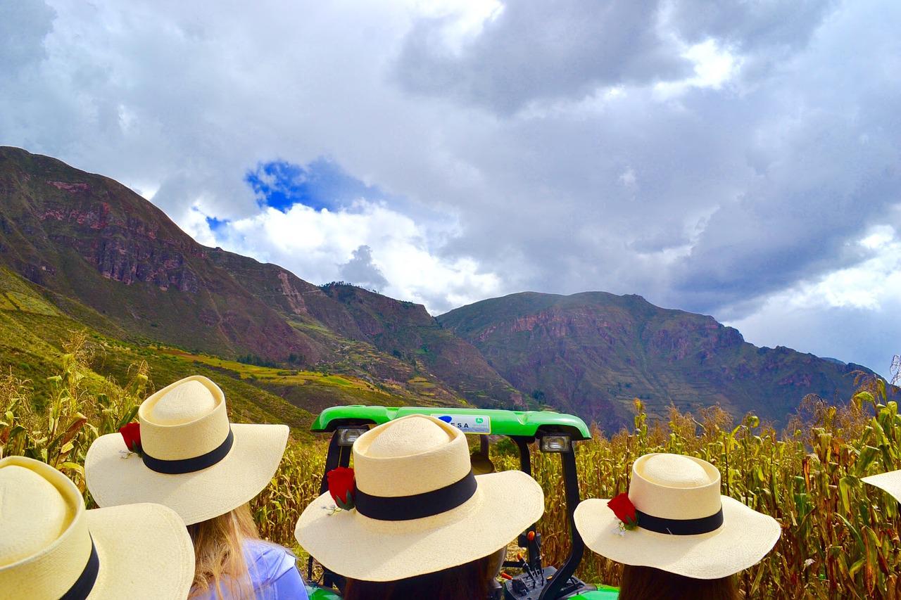 A group of women wearing floppy hats, looking out over the Sacred Valley in Macchu Picchu