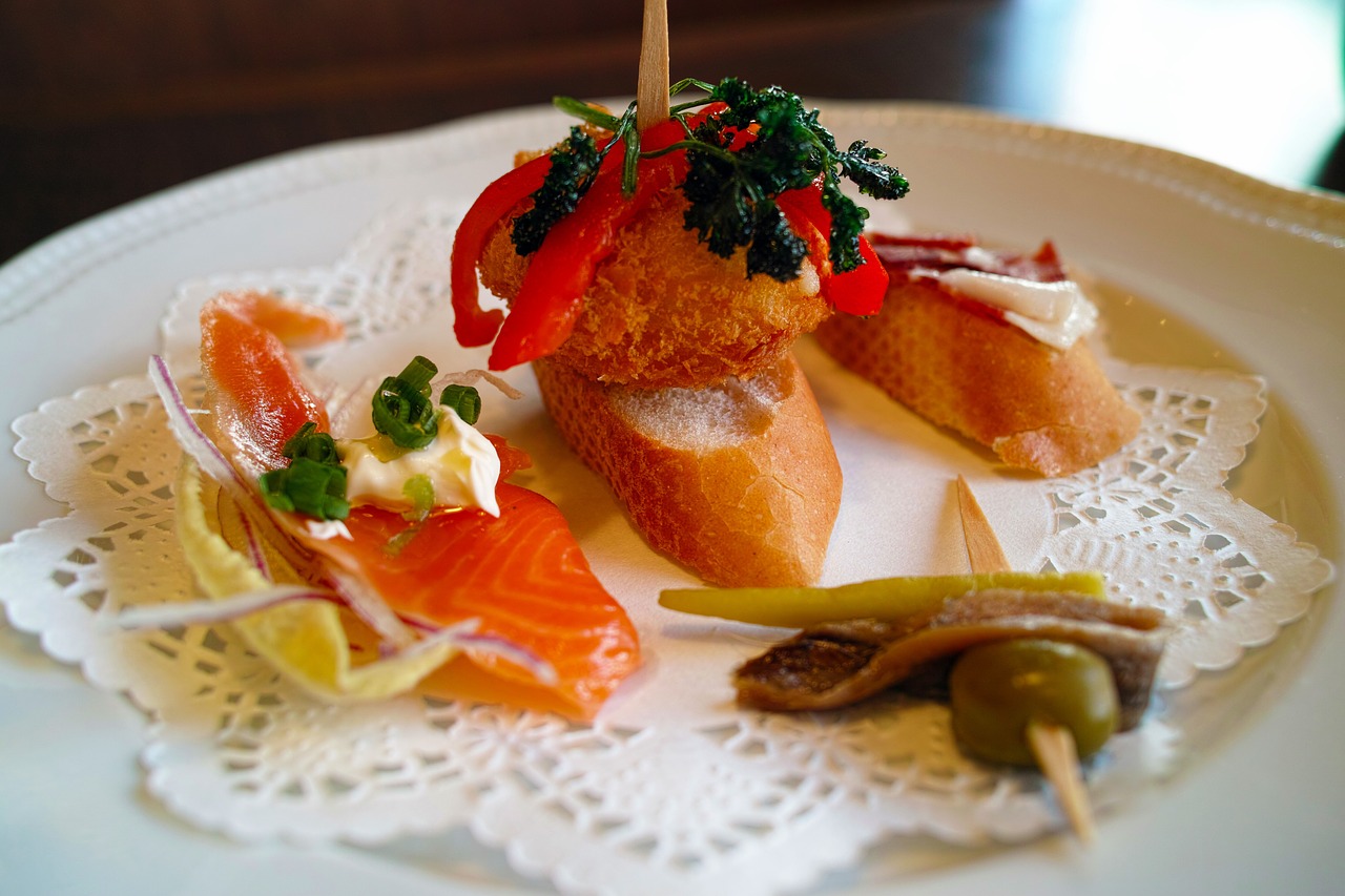 3-4 Spanish pintxos or pinchos sitting on a paper doily, on a plate