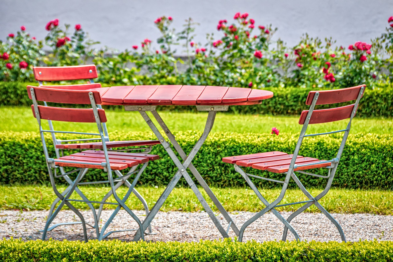 Al fresco dining at a restaurant - two red wooden folding chairs, set up in a pretty garden.