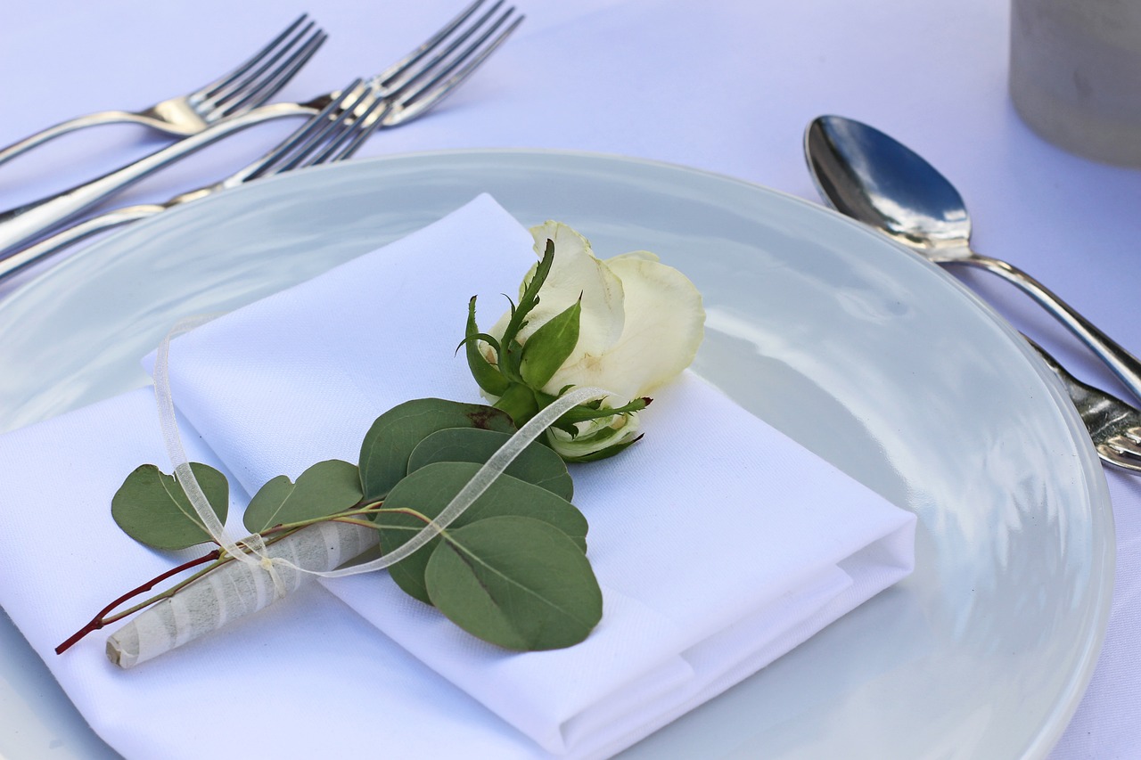 White rose on a napkin, on a plate, surrounded by cutlery