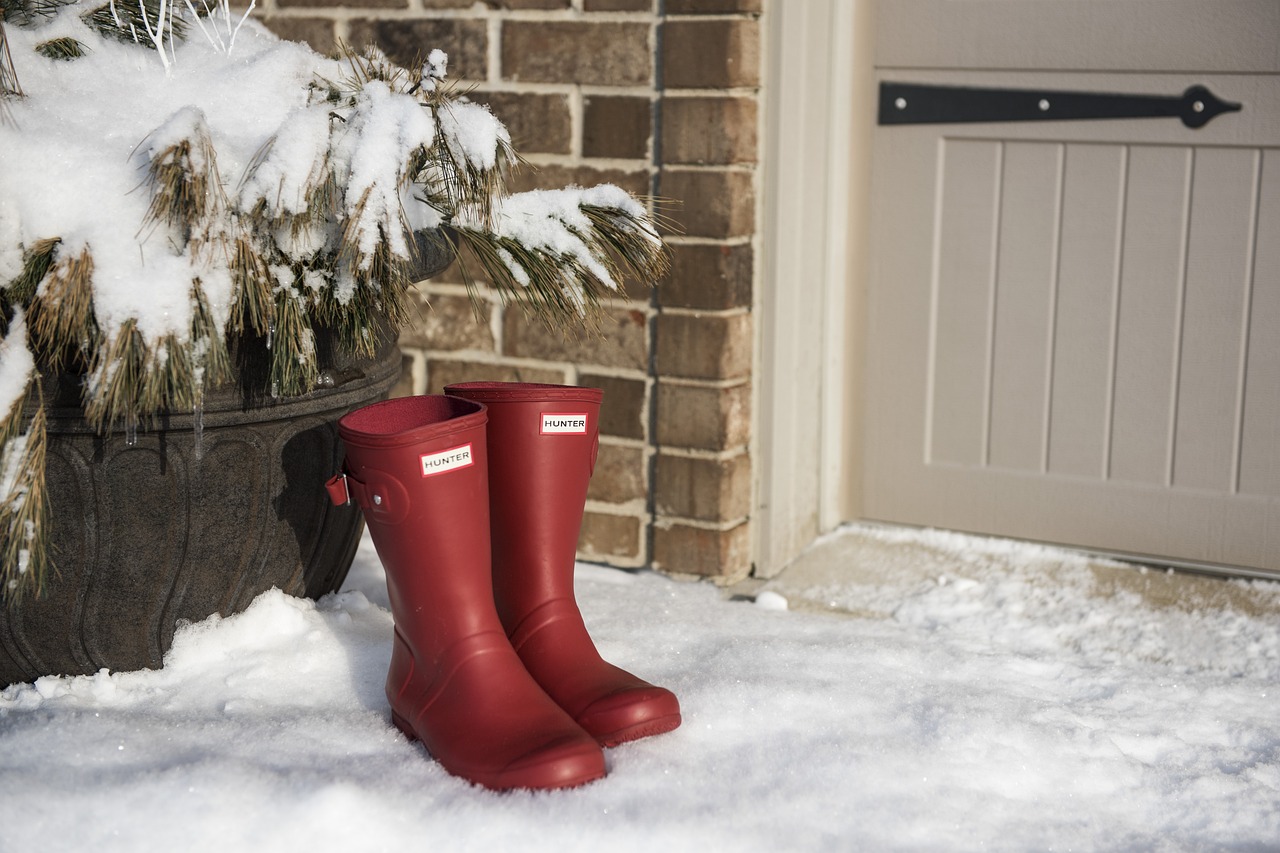 Red Hunter wellies sitting in the snow outside a door