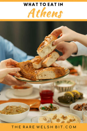 Hands reaching out to grab a selection of Greek food