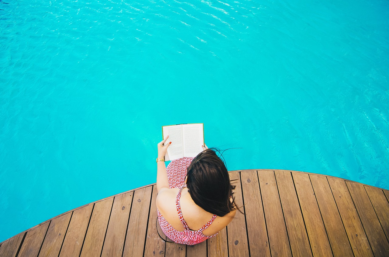 Girl reading a book next to the pool