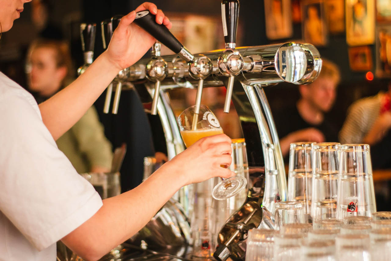 A hand pouring beer from a pump into a glass at Oktoberfest.