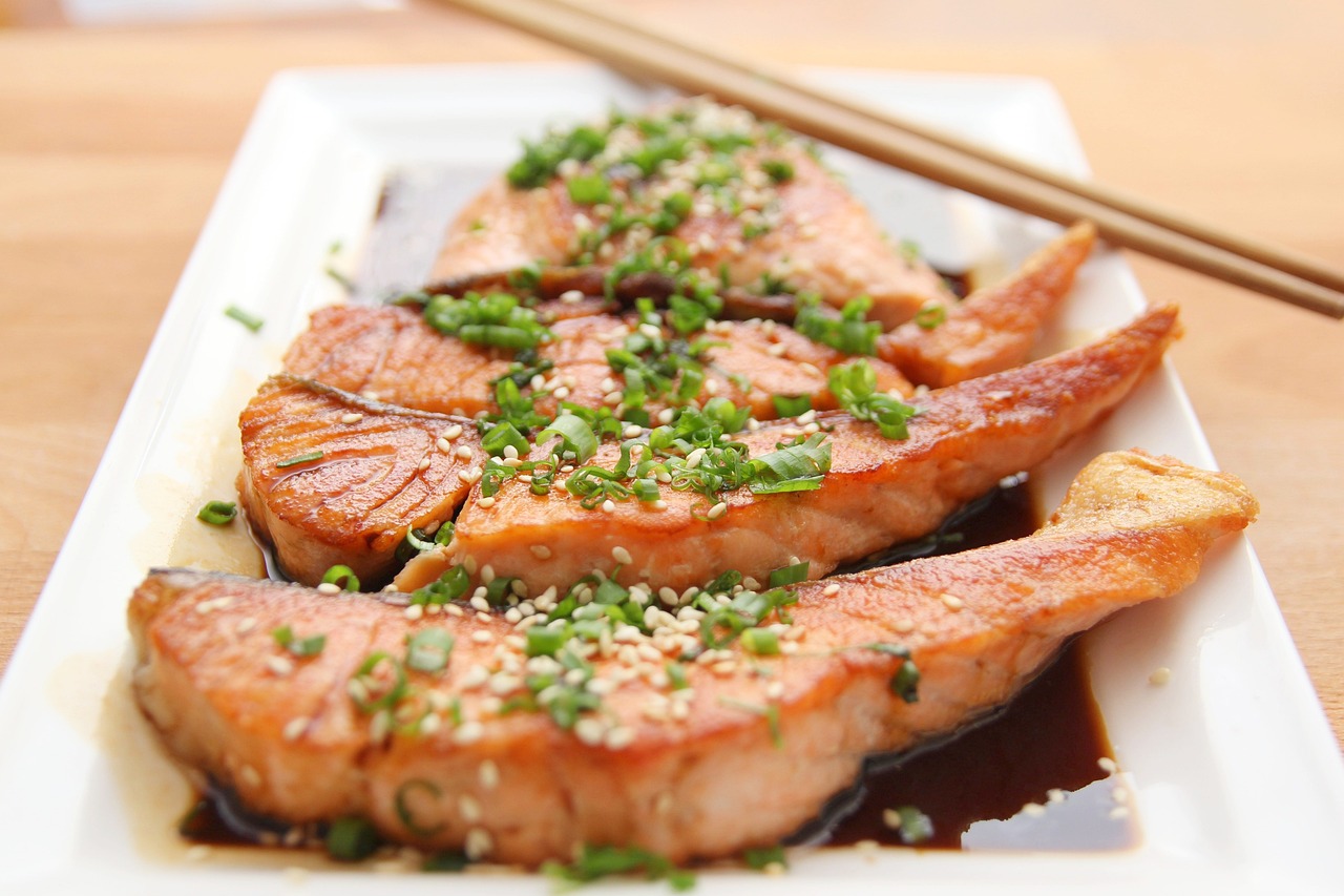 Salmon topped with spring onions and sesame seeds in teriyaki sauce