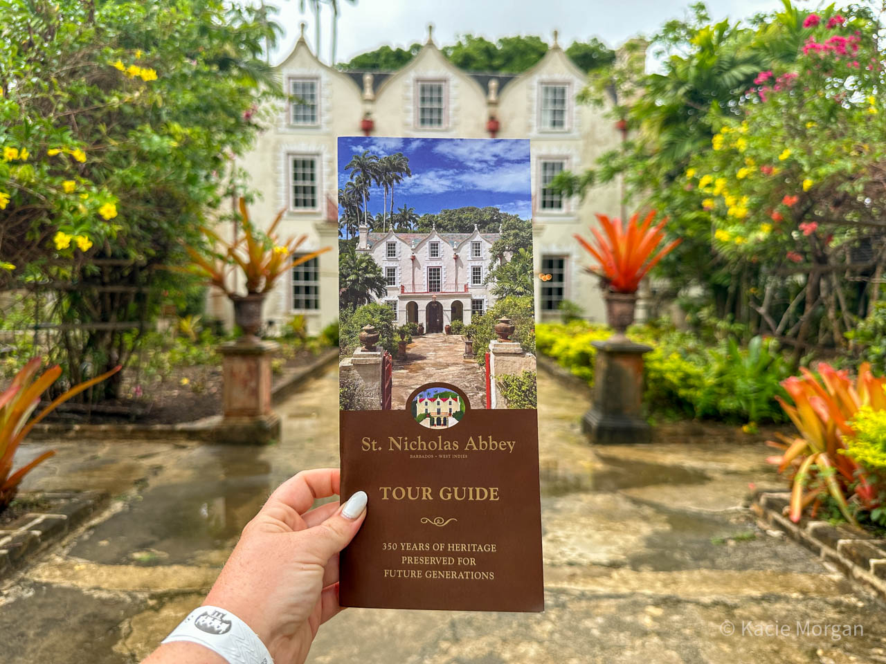 Holding the paper tour guide leaflet for St Nicholas Abbey, with the house in the background.