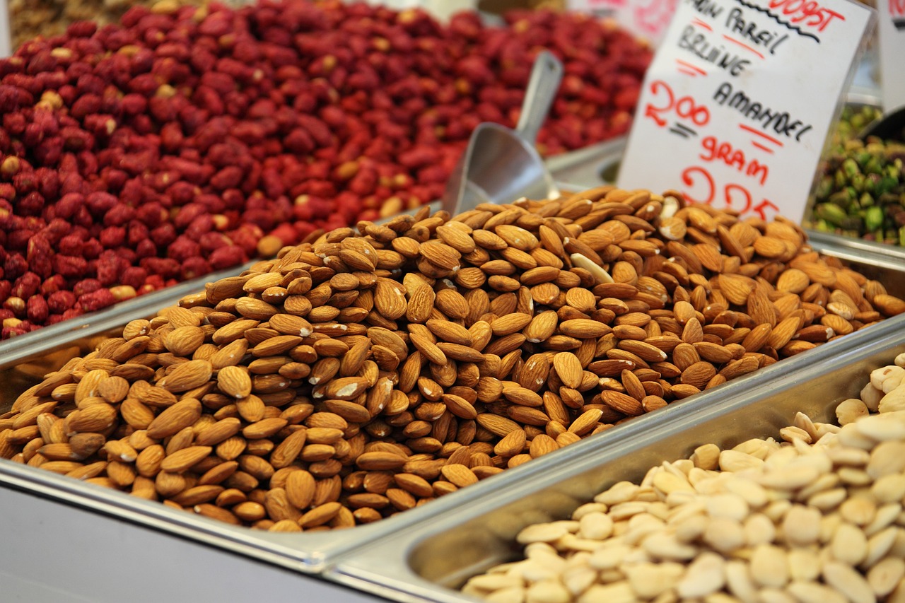 Almonds and other nuts on display in metal trays at a market