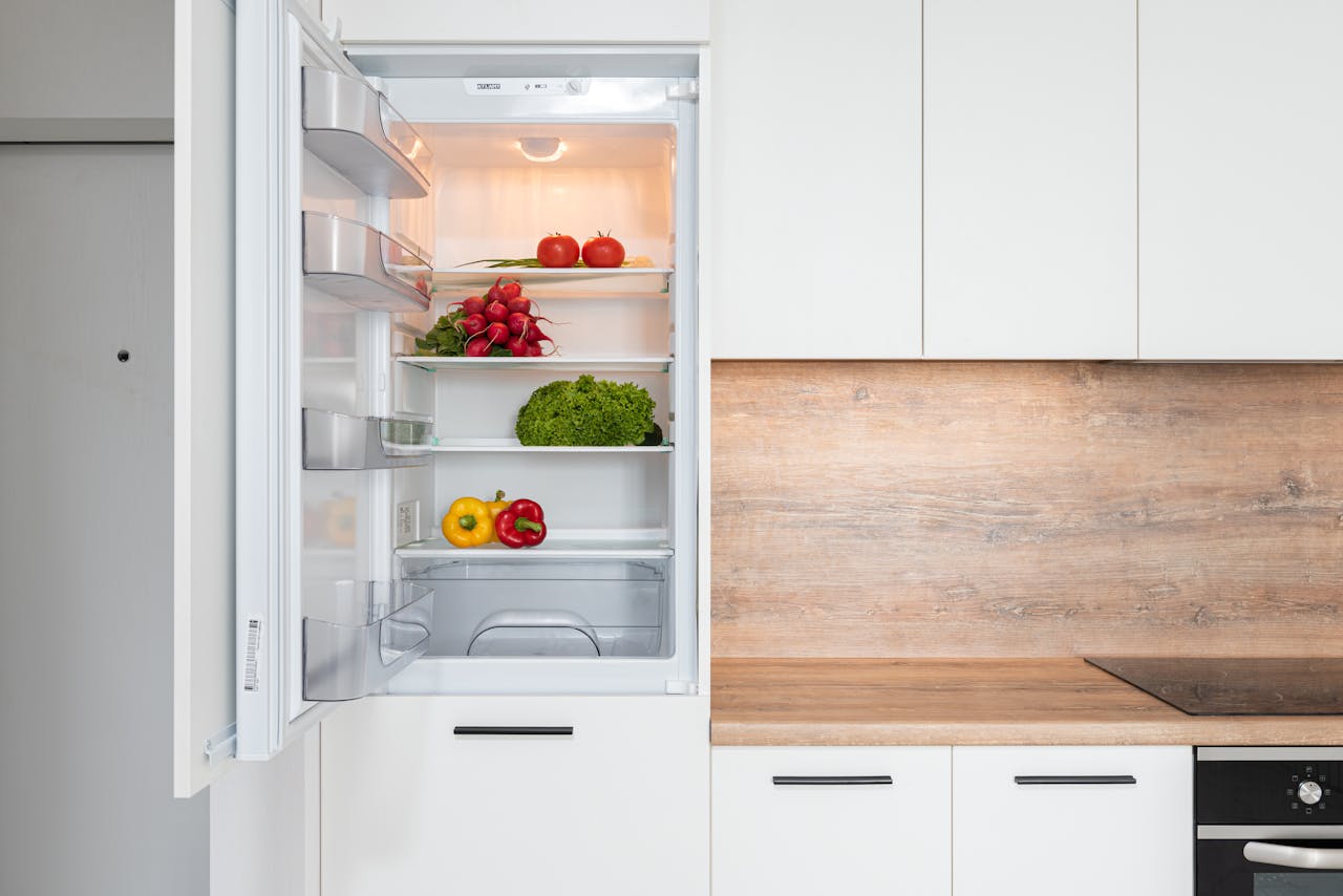 An open fridge door with vegetables in it.