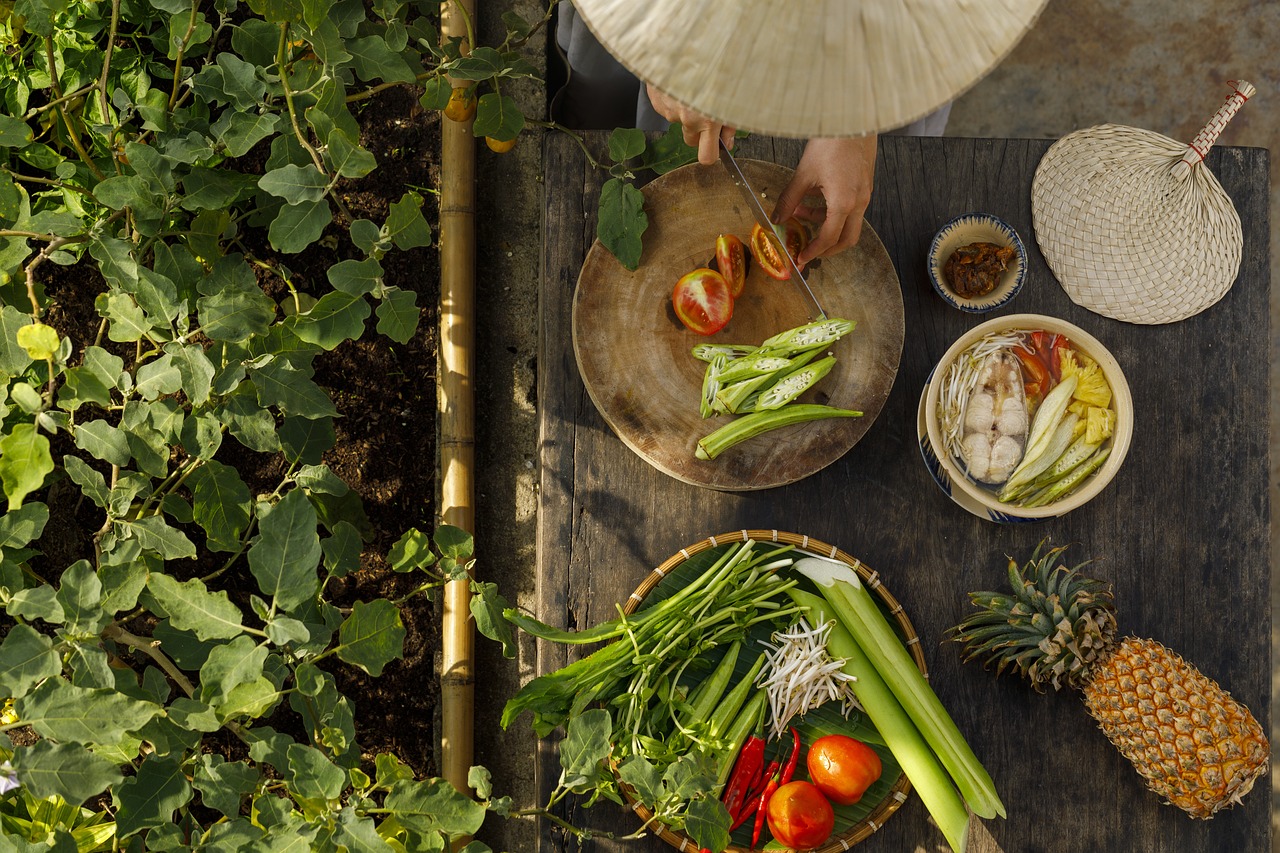 An overhead shot of a lady preparing fresh vegetables and spices on a chopping board.
